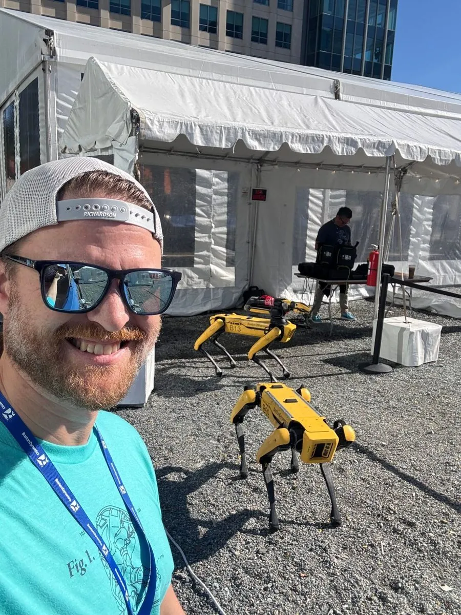 Michael O'Brien outdoors with two Boston Dynamics Spot robots behind him